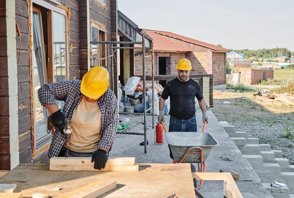 Dos personas obreras trabajan en la construcción de una vivienda.